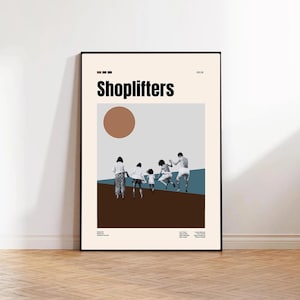 May include: A framed art print featuring the word "Shoplifters" in bold black letters. The artwork depicts a stylized scene of people running, set against a backdrop of brown, blue, and beige tones. A brown circle is above the figures.
