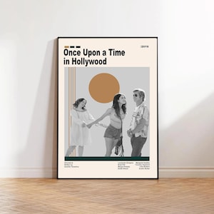 Może przedstawiać: Oprawiony plakat filmowy do filmu "Pewnego razu w Hollywood" z beżowym tłem, tytułem filmu i rokiem 2019. Plakat, z czarną ramą, przedstawia zdjęcie trzech aktorów.
