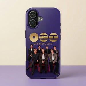 Puede incluir: Una funda de teléfono morada con un logotipo dorado y el texto "BTS SINCE 2013". La funda muestra una foto de siete personas. La funda del teléfono está diseñada para proteger el teléfono de arañazos y daños.