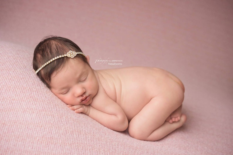 Dainty rhinestone headband for newborn photography, baptism, christening, or special occasion.  Small band of clear rhinestones with a gold finish and a simple gold rhinestone embellishment.  Simply stunning baby headband.