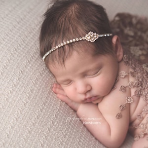 Dainty rhinestone headband for newborn photography, baptism, christening, or special occasion.  Small band of clear rhinestones with a gold finish and a simple gold rhinestone embellishment.  Simply stunning baby headband.