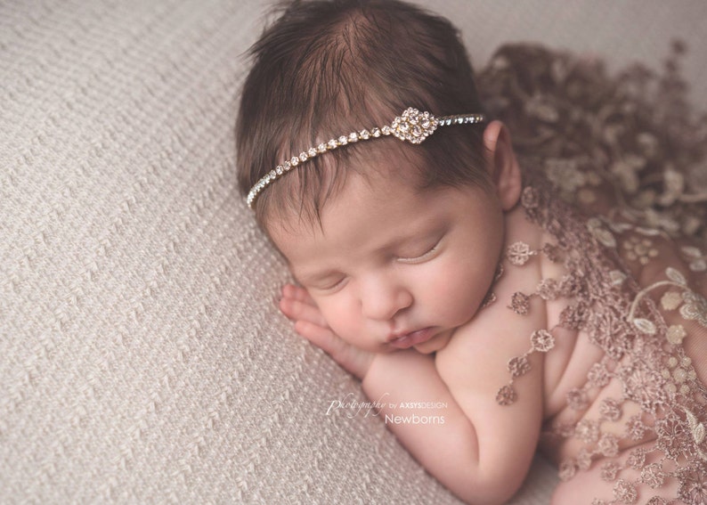 Dainty rhinestone headband for newborn photography, baptism, christening, or special occasion.  Small band of clear rhinestones with a gold finish and a simple gold rhinestone embellishment.  Simply stunning baby headband.