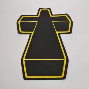 Peut inclure: Un objet noir de forme abstraite avec un contour jaune. La forme ressemble à une croix stylisée ou à une figure géométrique. L'objet est centré sur un fond blanc, créant un contraste visuel fort.