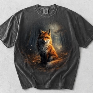 May include: Dark grey t-shirt with a detailed illustration of a fox in a forest. The fox is depicted with orange and white fur, set against a forest backdrop. The shirt has a vintage, worn appearance.