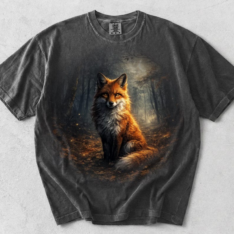 May include: Dark grey t-shirt with a detailed illustration of a fox in a forest. The fox is depicted with orange and white fur, set against a forest backdrop. The shirt has a vintage, worn appearance.