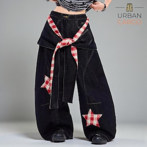 May include: Dark denim wide-leg trousers featuring red and white checked star appliqués and a matching checked belt. The trousers have a distinctive wrap-around waist design. The "Urban Cargo" logo is visible.