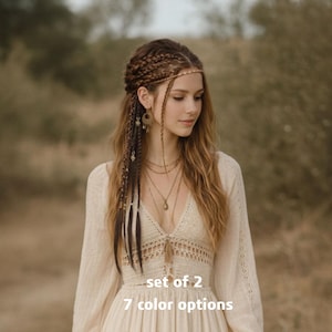 May include: A set of two hair extensions featuring braided brown strands with small metallic charms. The extensions are worn as part of a hairstyle. The image includes the text "set of 2" and "7 color options" overlaid on the lower portion.
