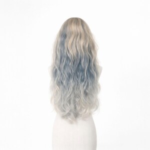 May include: A long, wavy wig with a blend of light blonde, blue, and silver tones. The wig is styled with loose, flowing waves and is displayed on a white mannequin head against a white background. The hair has a natural-looking texture.