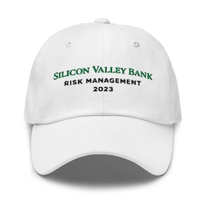 May include: A white baseball cap with the text "SILICON VALLEY BANK RISK MANAGEMENT 2023" in green and black. The cap has a curved brim and a button on top. This hat is a promotional item.
