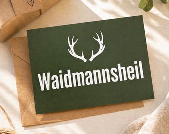 May include: A gift box with a tag that says "Für dich!" and a heart. A dark green card with white text that reads "Waidmannsheil" and a white antler design. The card is on a brown envelope.