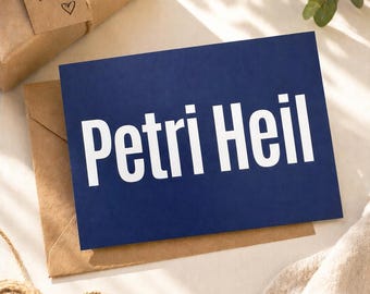 May include: A navy blue card with the words "Petri Heil" in large white letters, resting on a brown envelope. A wrapped gift with a tag that says "Für dich!" and a heart is in the background.
