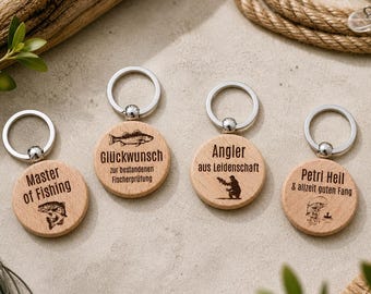 May include: Four wooden keychains with silver rings. Each keychain has a circular wooden pendant with engraved text and illustrations related to fishing. The text includes "Master of Fishing", "Glückwunsch", "Angler", and "Petri Heil".