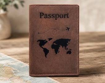 May include: A brown leather passport cover featuring the word Passport embossed at the top, a black world map graphic in the center, and a dashed flight path line with a small airplane icon above the map, finished with visible stitching.