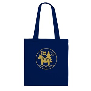 May include: A navy blue tote bag with a gold circular emblem featuring a horse, a flag, a tree, and a cloud. The bag has two navy blue handles.