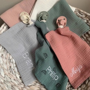 May include: A white ceramic mug with a black handle and the text "But First, Coffee" in a bold, black font. The mug is set against a blurred background, suggesting a cozy setting.