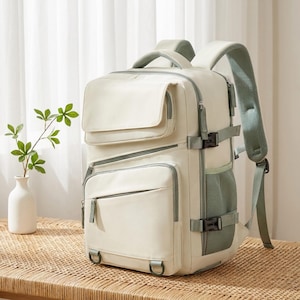 Peut inclure: Un sac à dos couleur crème doté de multiples compartiments zippés, d'une poche à rabat supérieure et de panneaux latéraux en maille vert sauge. Le sac comprend des sangles de compression latérales réglables avec des boucles en plastique noir.