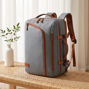 May include: A rectangular gray backpack featuring brown leather-like trim, multiple zippered compartments, a side handle, and adjustable shoulder straps. The design includes a diagonal front zipper and side compression buckles for secure storage.