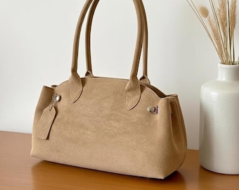 Bolso baguette de ante estilo francés, bolso de hombro, diseño vintage, bolso minimalista, asa superior estructurada, accesorio elegante y a la moda.