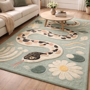 Puede incluir: Una alfombra azul claro con un diseño de serpiente caprichosa con manchas negras, beige y rosas. La alfombra también incluye grandes margaritas blancas y otros elementos florales y abstractos. La alfombra está colocada en un salón.