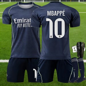 May include: A dark blue football kit comprising a jersey with Emirates Fly Better text, matching shorts, and a pair of dark blue socks. The back of the jersey features the name Mbappe and the number 10 in white, accompanied by black shin guards.