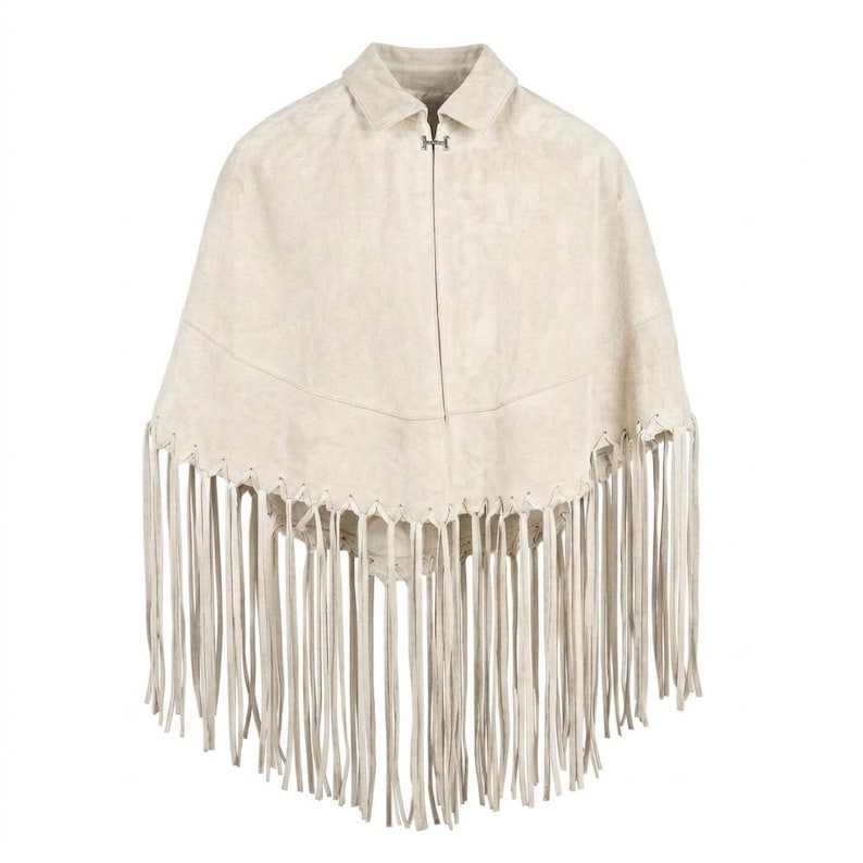 May include: A beige suede poncho featuring a classic collar, a single silver-toned metal hook-and-eye closure at the neckline, and a horizontal seam across the chest. The hem is finished with long, thin, matching beige suede fringe detailing.