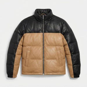 Puede incluir: Chaqueta acolchada de dos tonos con cuello alto. La parte superior de la chaqueta es negra, mientras que la parte inferior es de color canela. La chaqueta tiene una cremallera completa y dos bolsillos delanteros. La chaqueta es de cuero.