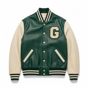 Op de afbeelding: Een groene en crèmekleurige varsity-jas met een groot "G" letterlogo. De jas heeft crèmekleurige mouwen, een gestreepte kraag, manchetten en zoom, en gouden drukknopen. Een jas in klassieke stijl.