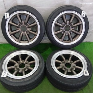 May include: Four black rubber tires mounted on bronze-colored eight-spoke metal wheels with silver rims. Each wheel is labeled with a small white square tag numbered one through four, positioned at the top or bottom of the tire assembly.