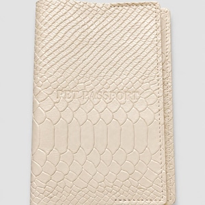 May include: A cream-colored rectangular pet passport cover featuring a textured snakeskin pattern across the entire surface. The words PET PASSPORT are embossed in the center of the cover in a clear, capitalized, sans-serif font style.