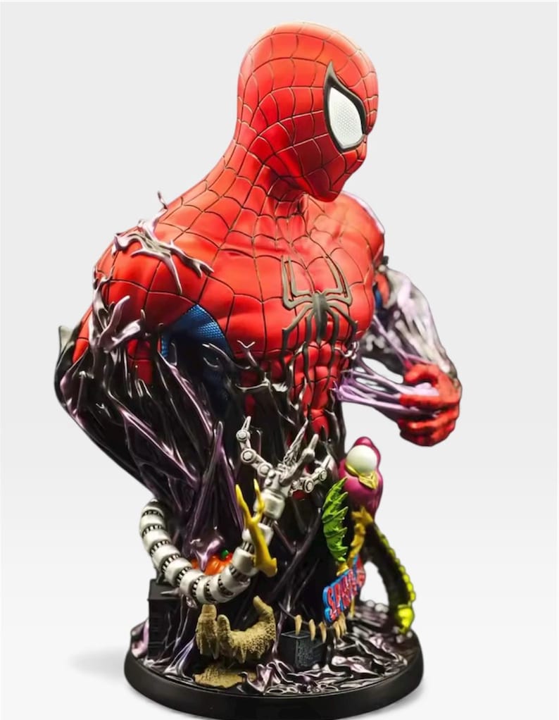 May include: A detailed bust of Spider-Man in a red and black suit, with a black spider emblem on the chest. The figure is partially engulfed in a dark, swirling substance, with mechanical arms and other elements at the base. The bust is a collectible item.