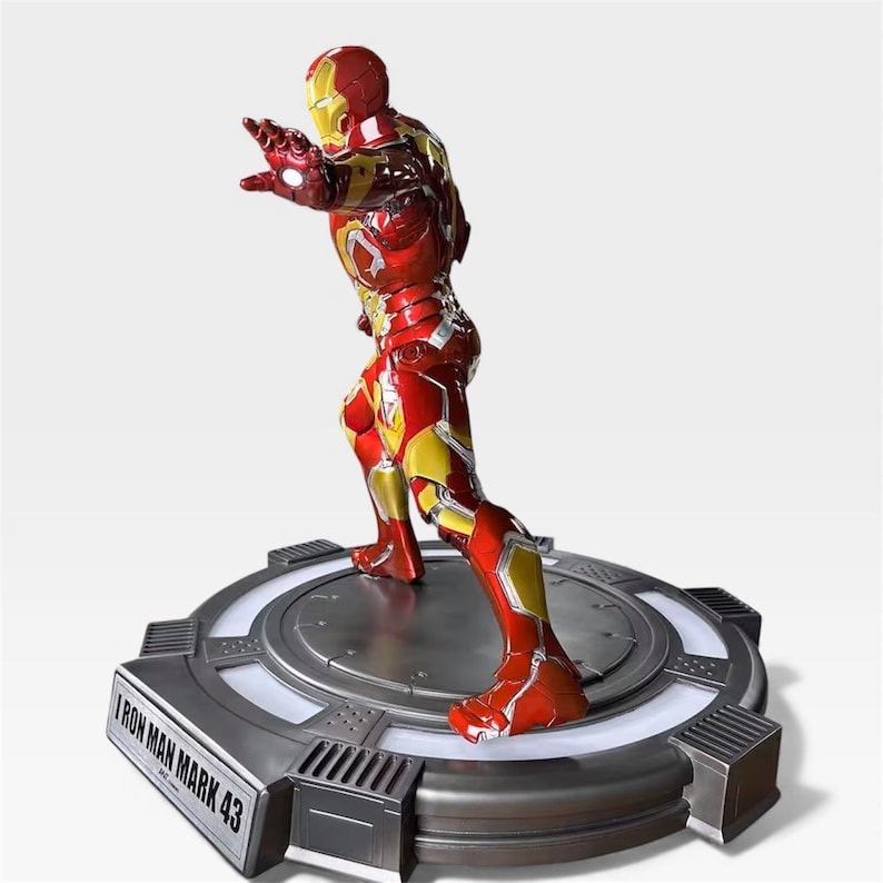 May include: A detailed Iron Man Mark 43 figurine in a dynamic pose, predominantly red and gold, with intricate armor detailing. The figure is mounted on a circular, metallic base with the text "Iron Man Mark 43".