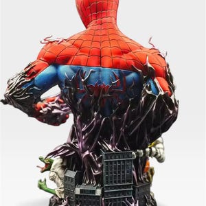 May include: A detailed Spider-Man bust statue, viewed from the back, showcasing the character's red and blue suit with intricate web detailing. The statue features a black, textured base with miniature buildings and figures, and a dark, organic design element.