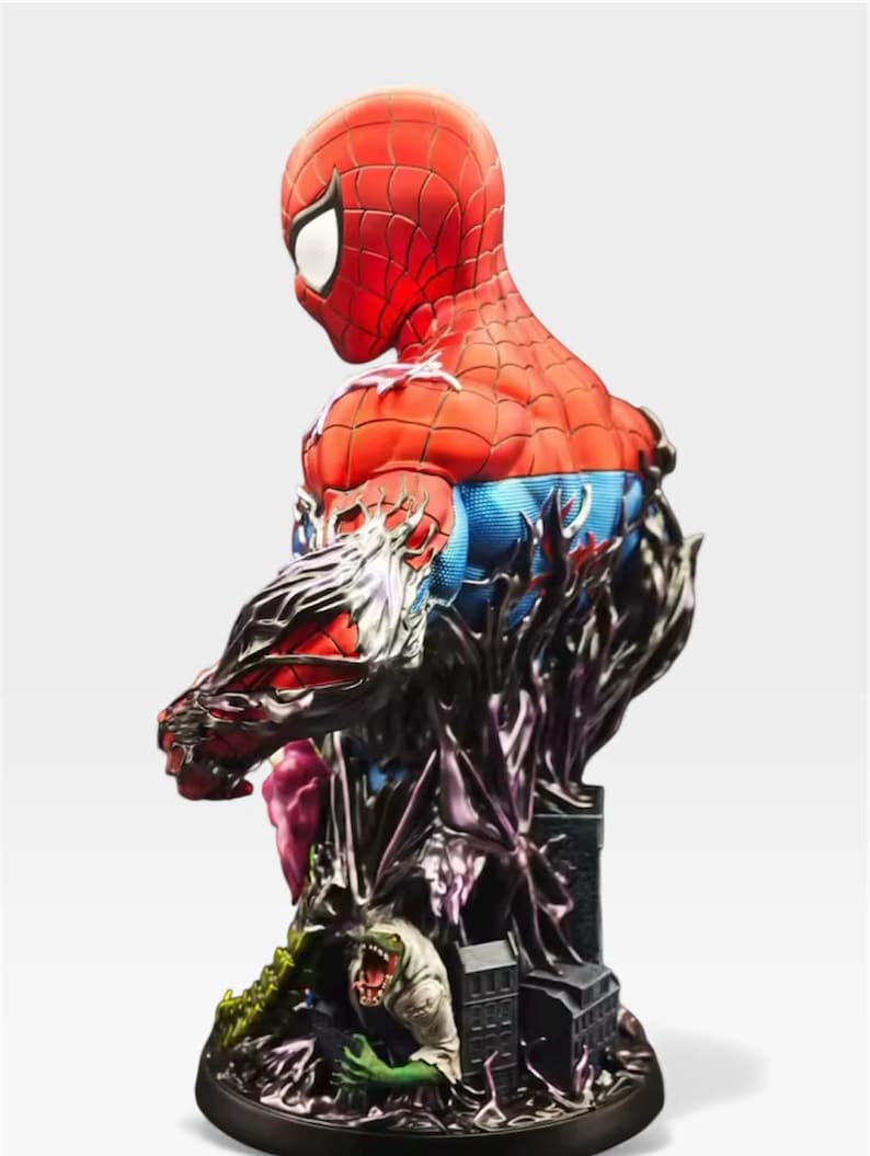 May include: A detailed Spider-Man bust statue, mainly red and blue, in a dynamic pose. The statue has intricate detailing, including a black, textured base with a cityscape and a monster. The design is a blend of comic book and artistic elements.