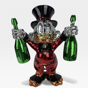Puede incluir: Escultura metálica de un personaje de pato con traje rojo y sombrero de copa negro, sosteniendo dos botellas de champán verdes. El pato tiene una cara plateada, detalles dorados y zapatos negros. La escultura tiene un acabado brillante.