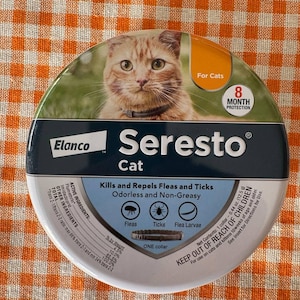 May include: Round container of Seresto Cat flea and tick collar. The product image features a cat and text that reads "Kills and Repels Fleas and Ticks" and "8 Month Protection". The container is white and blue.
