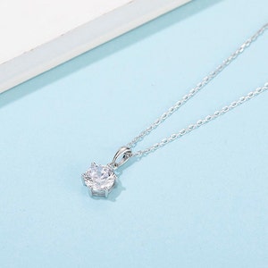 Un solitario de diamante moissanita brilla en este delicado colgante de plata esterlina.