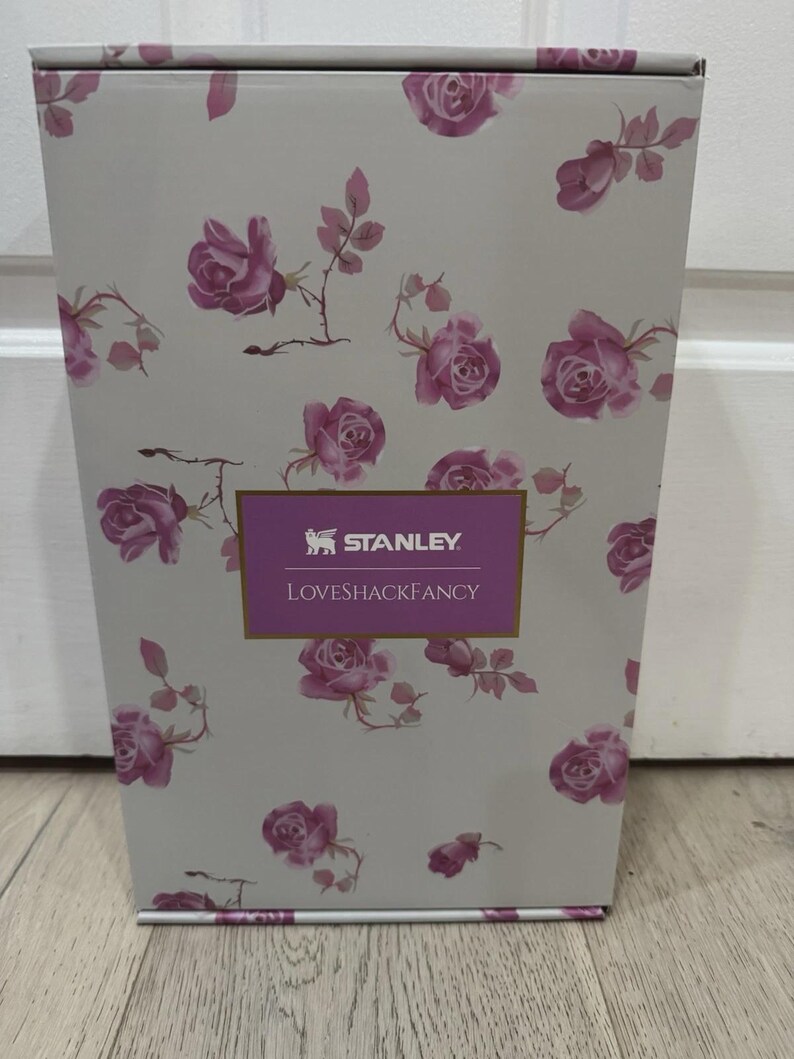 May include: A rectangular box with a floral rose pattern in pink and white. The box has the text "STANLEY LOVESHACKFANCY" in a purple rectangle.