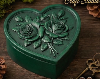 May include: A heart-shaped, dark green box with a detailed relief of roses on the lid. The box is labeled "Design by Fortuna Craft Studio" and "STL FILE". Decorative keys and foliage are in the background.