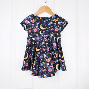 May include: A black short-sleeved dress with a floral and crescent moon print. The dress has a flared skirt and a round neckline.