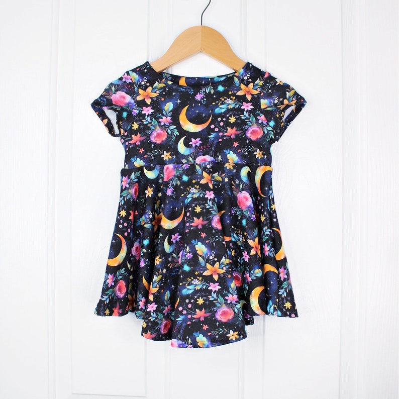 May include: A black short-sleeved dress with a floral and crescent moon print. The dress has a flared skirt and a round neckline.