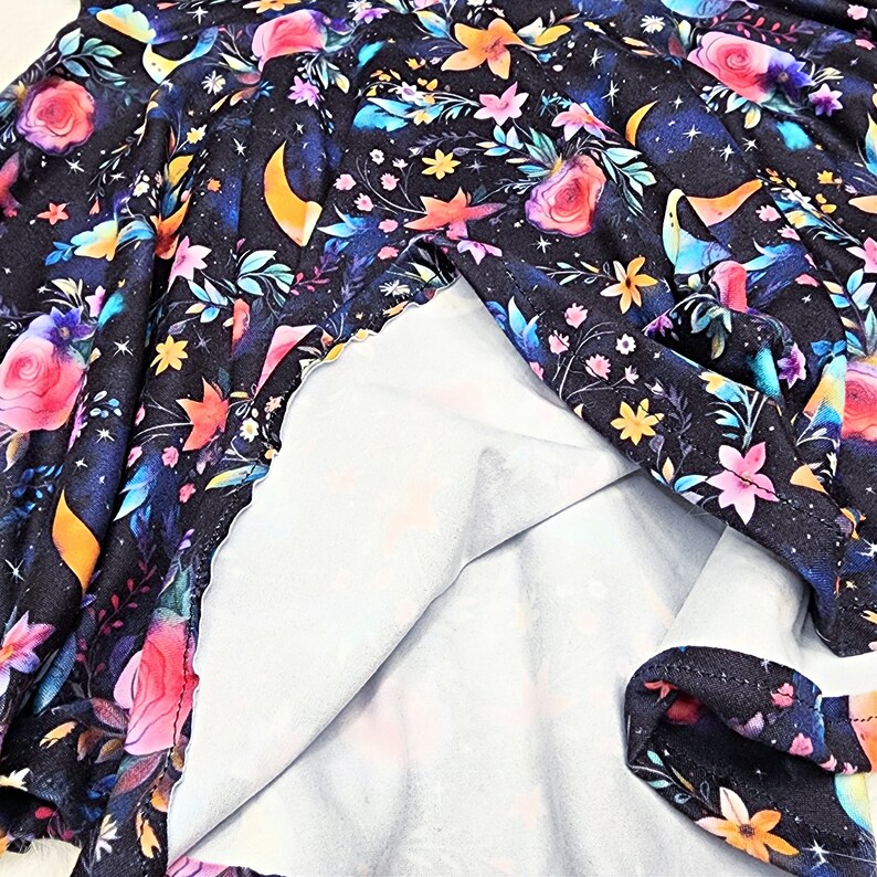 May include: Black fabric with a floral and crescent moon print. The fabric is folded in half, revealing a white lining.
