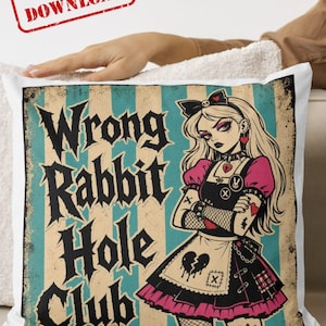 K&ouml;nnte beinhalten: Ein quadratisches Dekokissen mit einem vertikal gestreiften Hintergrund in T&uuml;rkis und Creme und dem Text Wrong Rabbit Hole Club in schwarzer gotischer Schrift. Eine Illustration einer blonden Figur in einem schwarz-pinken Kleid mit Herzmotiv.