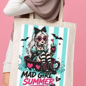 K&ouml;nnte beinhalten: Eine beige Stofftasche aus Segeltuch mit einem Grafikdruck einer Figur mit wei&szlig;em Haar, herzf&ouml;rmiger Sonnenbrille und schwarzen Stiefeln, die in einer Teetasse sitzt. Der Hintergrund hat hellblaue und wei&szlig;e Streifen, Text MAD GIRL SUMMER.