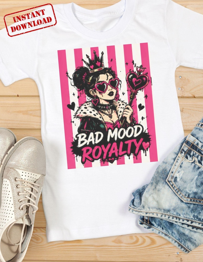 K&ouml;nnte beinhalten: Ein wei&szlig;es T-Shirt mit einer Grafik einer Person, die eine Krone, herzf&ouml;rmige Sonnenbrillen und eine Jacke mit Pelzkragen tr&auml;gt und ein herzf&ouml;rmiges Zepter h&auml;lt. Das Design zeigt rosa vertikale Streifen und den Text BAD MOOD ROYALTY in Schwarz und Pink.