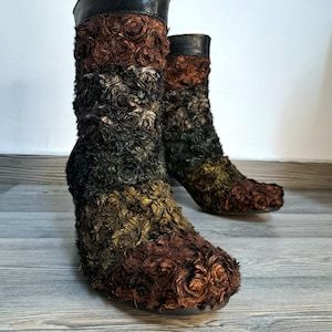 Op de afbeelding: Een paar unieke enkellaarsjes met een textuurrijk, veelkleurig ontwerp. De laarsjes hebben een kleurengradatie, waaronder bruin, zwart en goud, met een imitatiebont-achtige textuur. De bovenkant van de laarsjes is van zwart, slangenleerachtig materiaal.