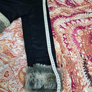 K&ouml;nnte beinhalten: Schwarze Jacke mit Kunstfellbesatz an den Manschetten und am Kragen. Die Jacke wird mit einem Ma&szlig;band gemessen. Die L&auml;nge der Jacke betr&auml;gt ca. 147 cm.