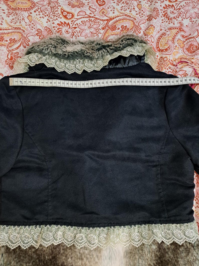 K&ouml;nnte beinhalten: Schwarze Jacke mit Kunstfellkragen und -besatz. Die Jacke hat eine Spitzendetail am unteren Rand. Die Breite der Jacke betr&auml;gt ca. 114 cm am R&uuml;cken.