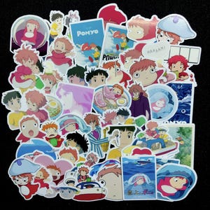 Pu&ograve; includere: Una collezione di adesivi colorati con personaggi e scene del film d'animazione "Ponyo". Gli adesivi mostrano varie pose ed espressioni dei personaggi, con testo come "Ponyo" e "Haaam!"