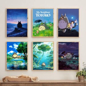 May include: Six framed art prints featuring scenes from the animated film "My Neighbor Totoro." The prints depict Totoro in various settings, including a night scene, a field, and a pond. The prints are in wooden frames.