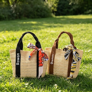 May include: Two straw tote bags with black and brown handles, personalized with names. Each bag features a colorful scarf tied to the handle. One bag has the name "Rowan" and the other has the name "Genevieve".